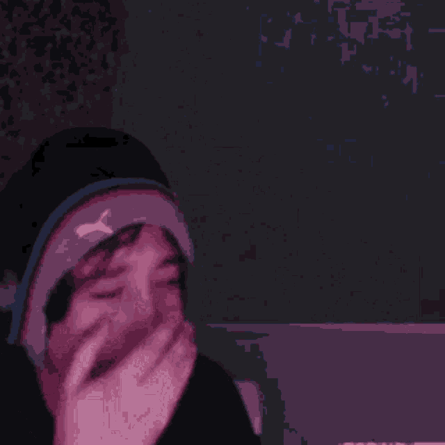 a person wearing a headband and a hat is making a funny face in a dark room .