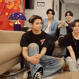 a group of young men are sitting on the floor in front of a couch ..