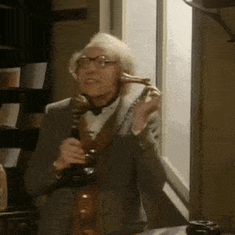a man in a suit and tie is talking on a telephone in front of a window .