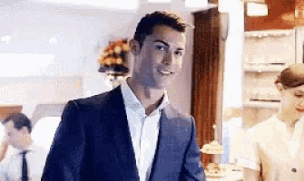 a man in a suit and white shirt is standing in a kitchen .