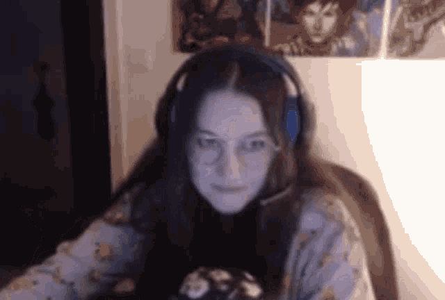 a woman wearing headphones and glasses is sitting in front of a computer screen .