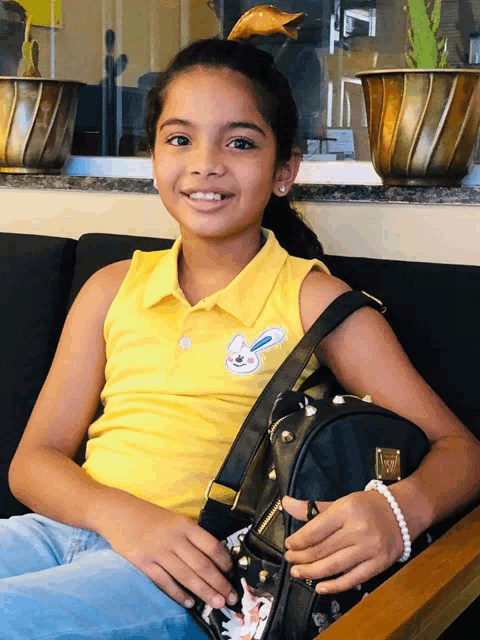 a girl in a yellow shirt holds a black bag