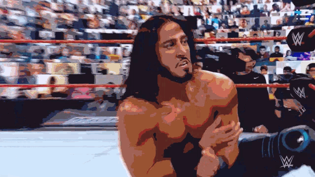 a man with long hair is in a wrestling ring with a w logo