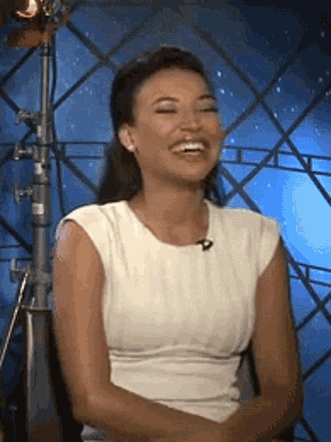 a woman in a white shirt is laughing and smiling