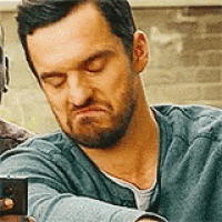 a man with a beard is making a funny face while sitting down with his eyes closed .