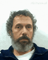 a man with a beard and curly hair is wearing a blue jacket and a white shirt