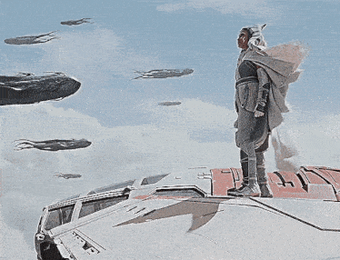 a man is standing on top of a space ship with a few ships flying in the background