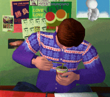 a man in a purple sweater sits in front of a wall with posters on it including one that says love love