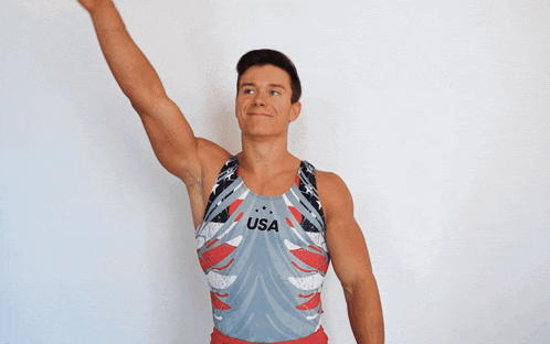 a man wearing a usa tank top holds his hands up