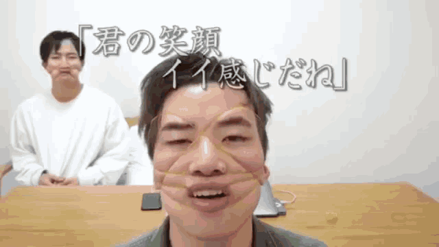 a man is making a funny face in front of a sign that says ' 君 の 笑顔 '