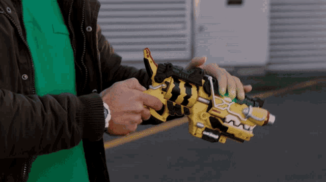a man in a green shirt and brown jacket is holding a yellow toy gun