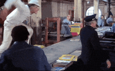 a man in a hard hat stands in front of a conveyor belt holding a sign that says ' safety ' on it