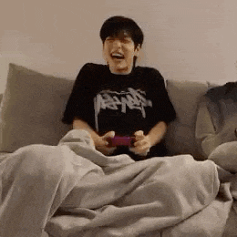 a young man is sitting on a couch playing a video game .