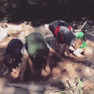 a group of people are kneeling down in the dirt looking for something