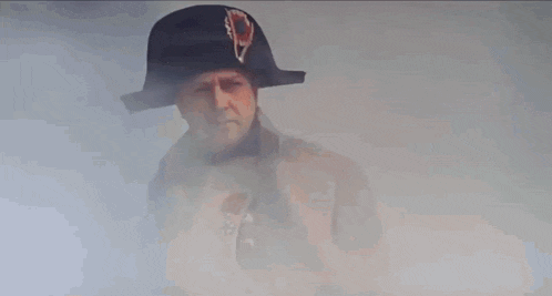 a man in a napoleon hat and coat is standing in front of a building .