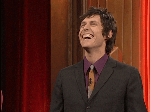 a man in a suit and tie is laughing with his mouth open