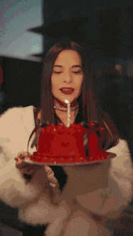 a woman is blowing out a candle on a red cake