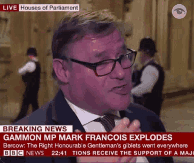 a man in a suit and tie is talking on a bbc news channel