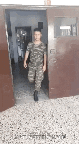 a man in a military uniform is walking out of a doorway .