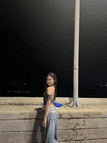 a woman in a leopard print top and jeans is standing on a wall