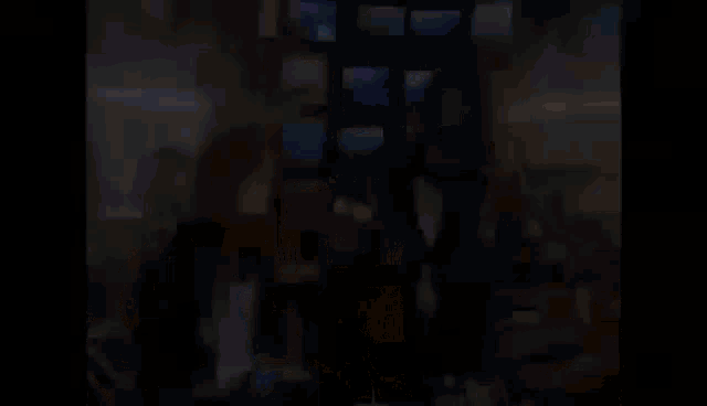 a couple of people standing next to each other in a room with a bunch of monitors .