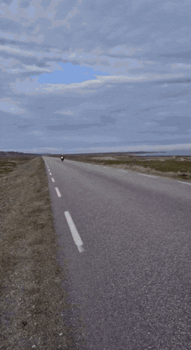 a person is riding a motorcycle down a road with a motorcycle mirror in the foreground .