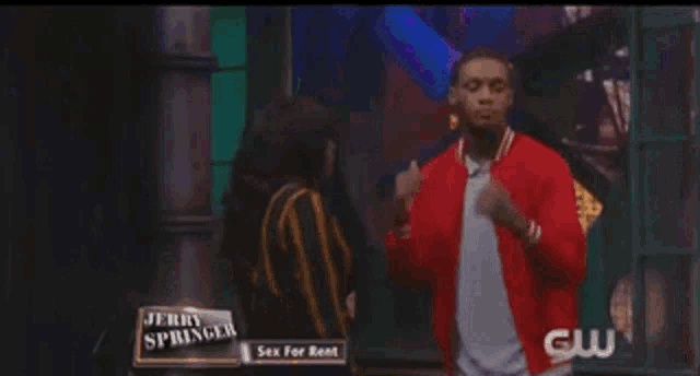 a man in a red jacket is dancing in front of jerry springer