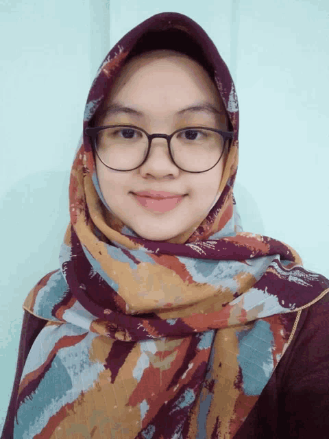 a woman wearing glasses and a scarf is smiling