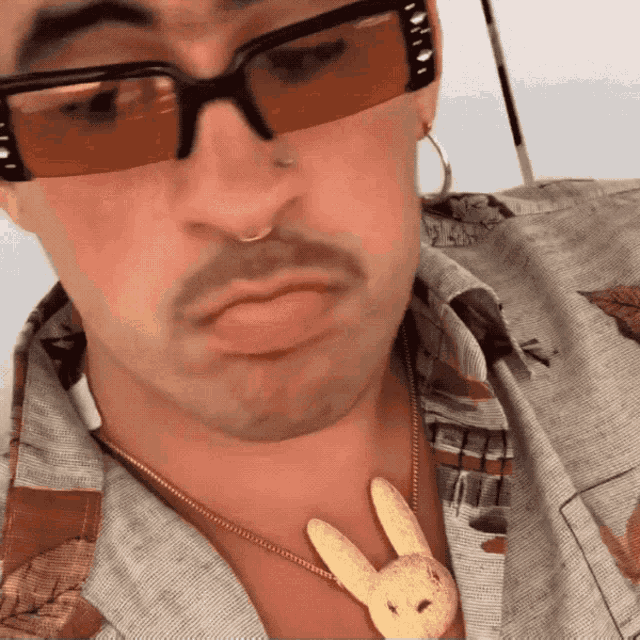 a man wearing sunglasses and a necklace with a stuffed bunny on it