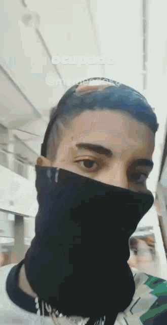 a man wearing a black scarf around his face with the word ocupado written above him