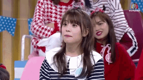 a girl in a striped shirt is sitting in a row with other girls .