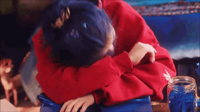 a woman with blue hair wearing a red sweater is laying down