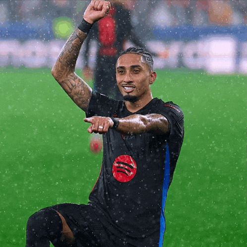 a soccer player wearing a black shirt with a red spotify logo on it