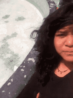 a woman with curly hair and a nose ring is making a funny face