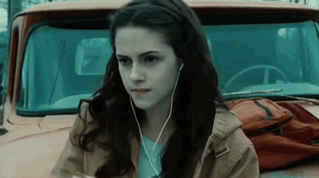 a woman wearing earbuds is sitting in front of a truck