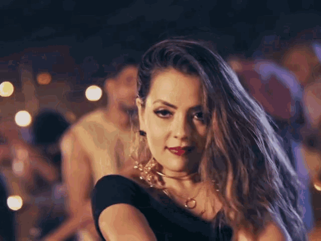 a woman wearing a choker and earrings is looking at the camera