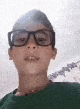 a young boy wearing glasses and a green shirt is making a face .