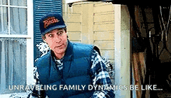 a man in a baseball cap and vest is standing in front of a house .