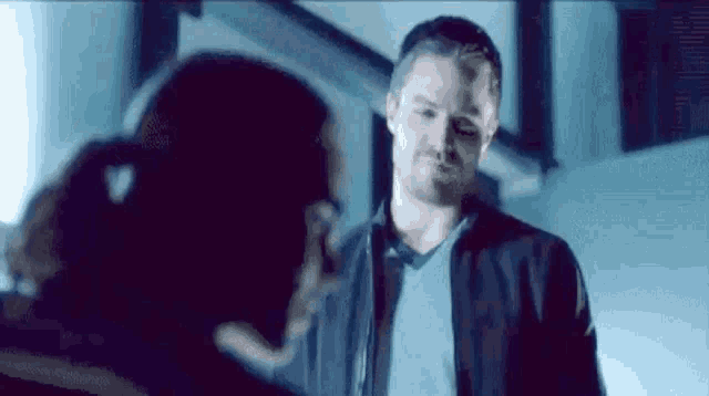 a man and a woman are standing next to each other in a dark room and talking to each other .