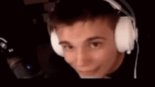 a man wearing headphones is making a funny face while looking at a computer screen .