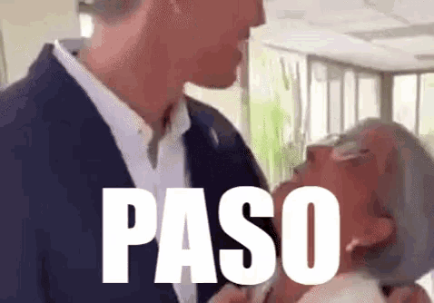 a man in a suit is kissing an older woman 's neck and the word paso is on the screen