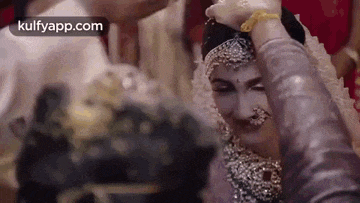 a man is putting a ring on a woman 's head .