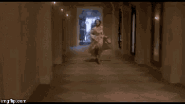 a woman in a white dress is running down a hallway in a hallway .