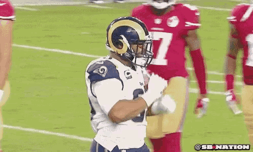 a football player wearing a rams helmet stands on the field