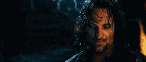 a close up of a man 's face in the dark with a beard and long hair .