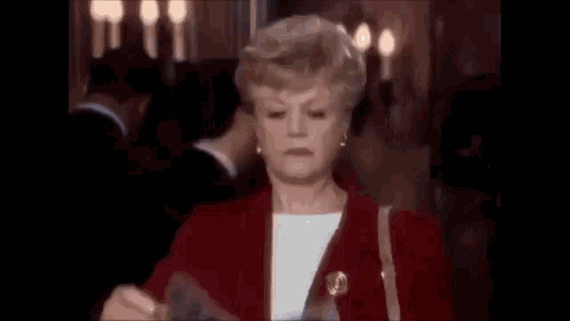 a woman in a red jacket is holding a piece of paper in her hand .