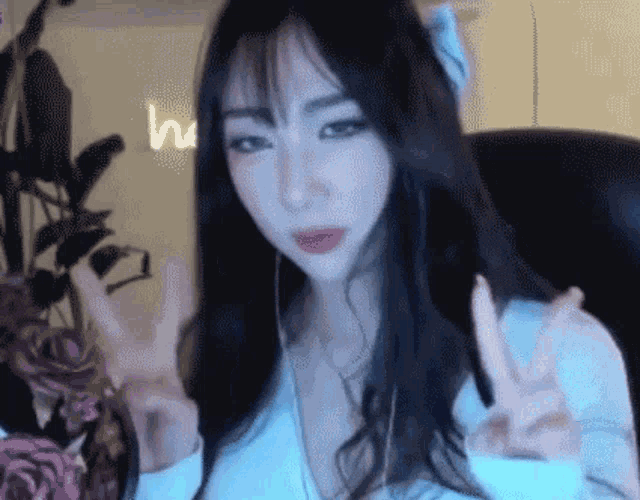 a woman with long hair is giving a peace sign