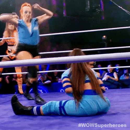 two women wrestling in a ring with #wowsuperheroes written on the bottom right