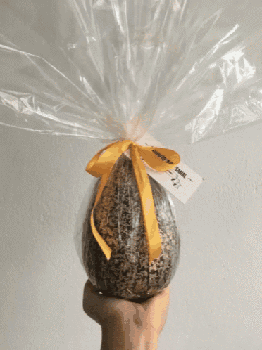 a person is holding a bread wrapped in plastic with a tag that says sana on it