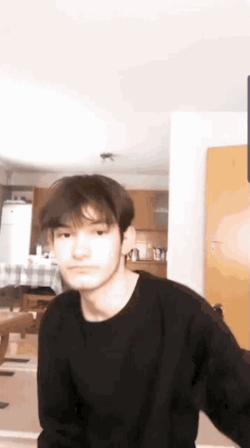 a young man in a black shirt is standing in a living room .